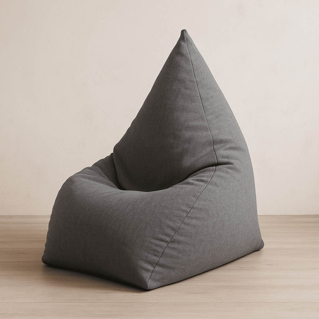 פוף שפיץ אפור בצורת קונוס מונח על רצפת עץ בהירה בחדר מודרני מינימליסטי.